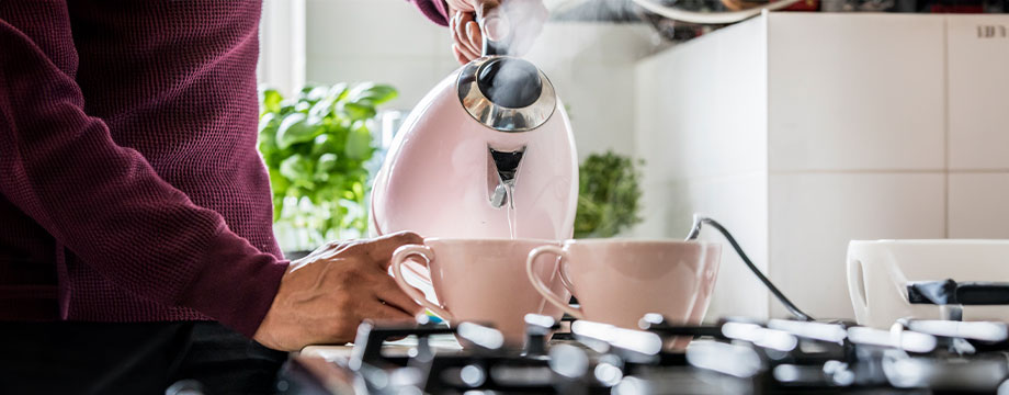 A person pouring water from a kettle into teacups