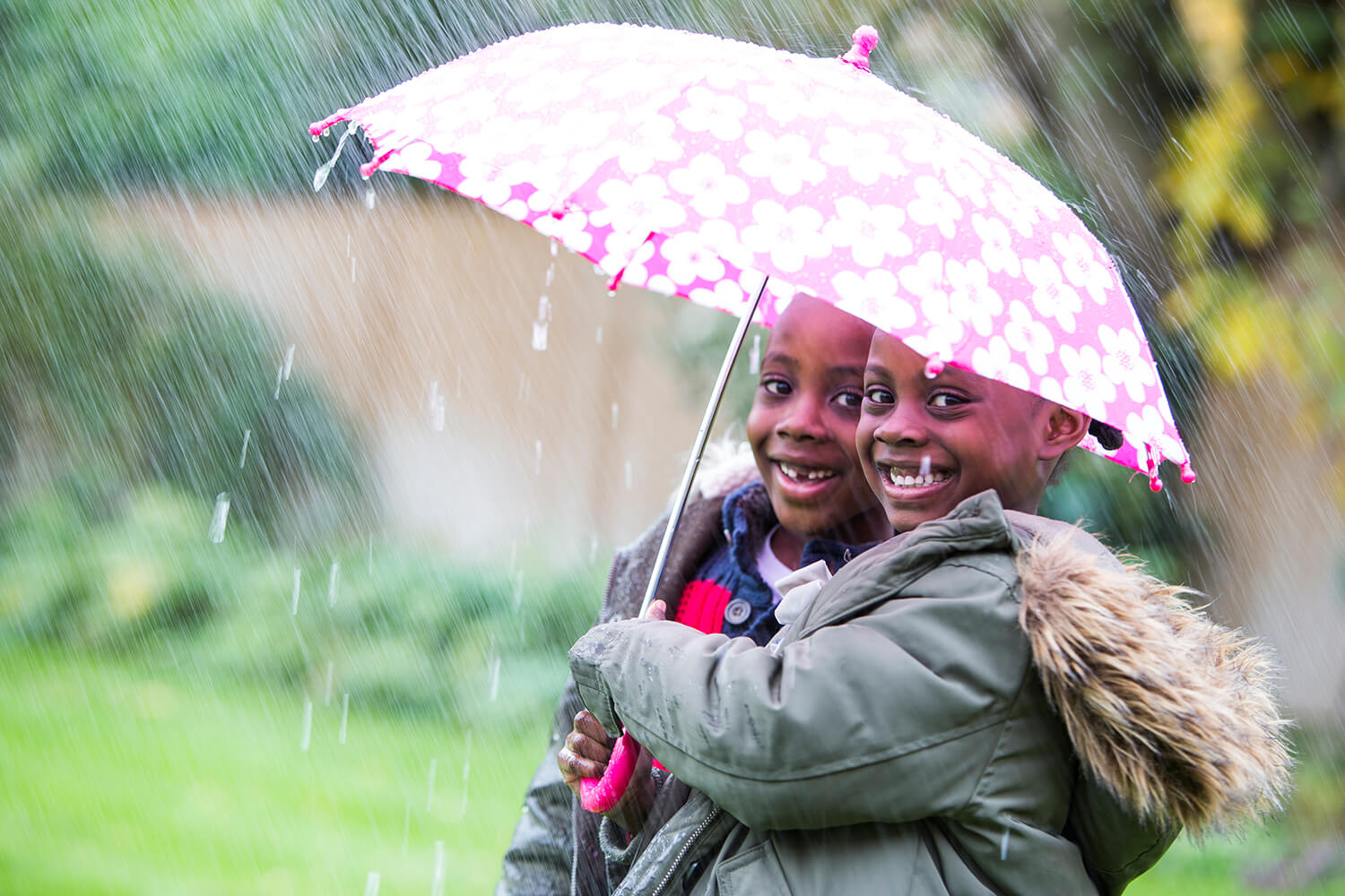 Two children shelter from the rain under an umbrella