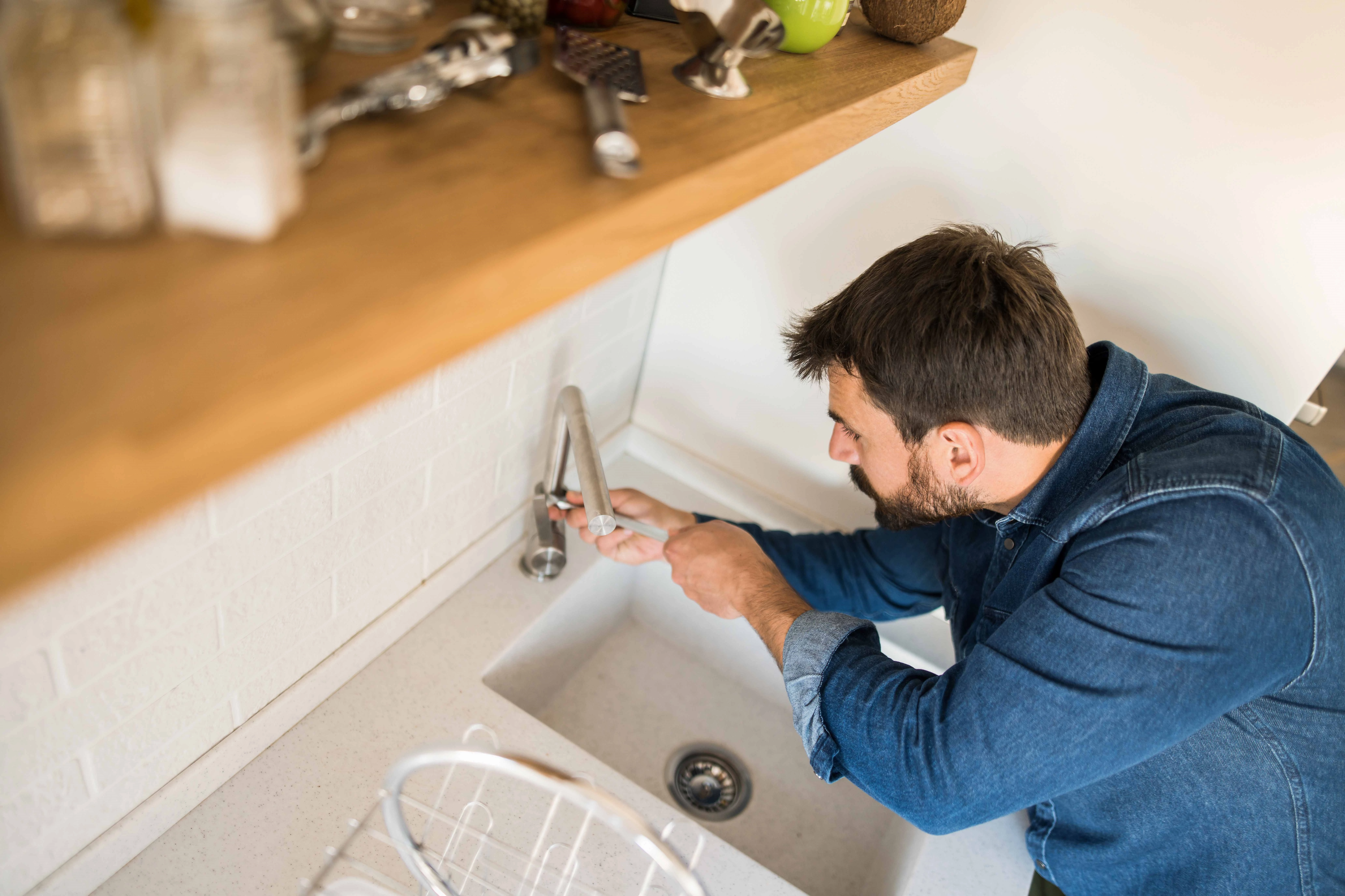 A man fixes a leaky dripping tap in his home.