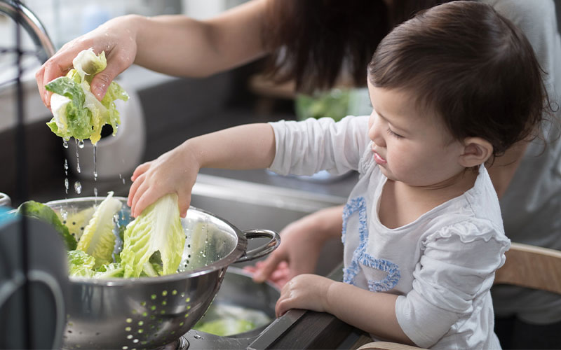 A child rinses food in the sink