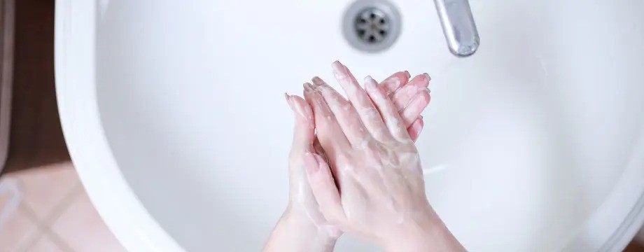 Pair of hands being washed in a sink