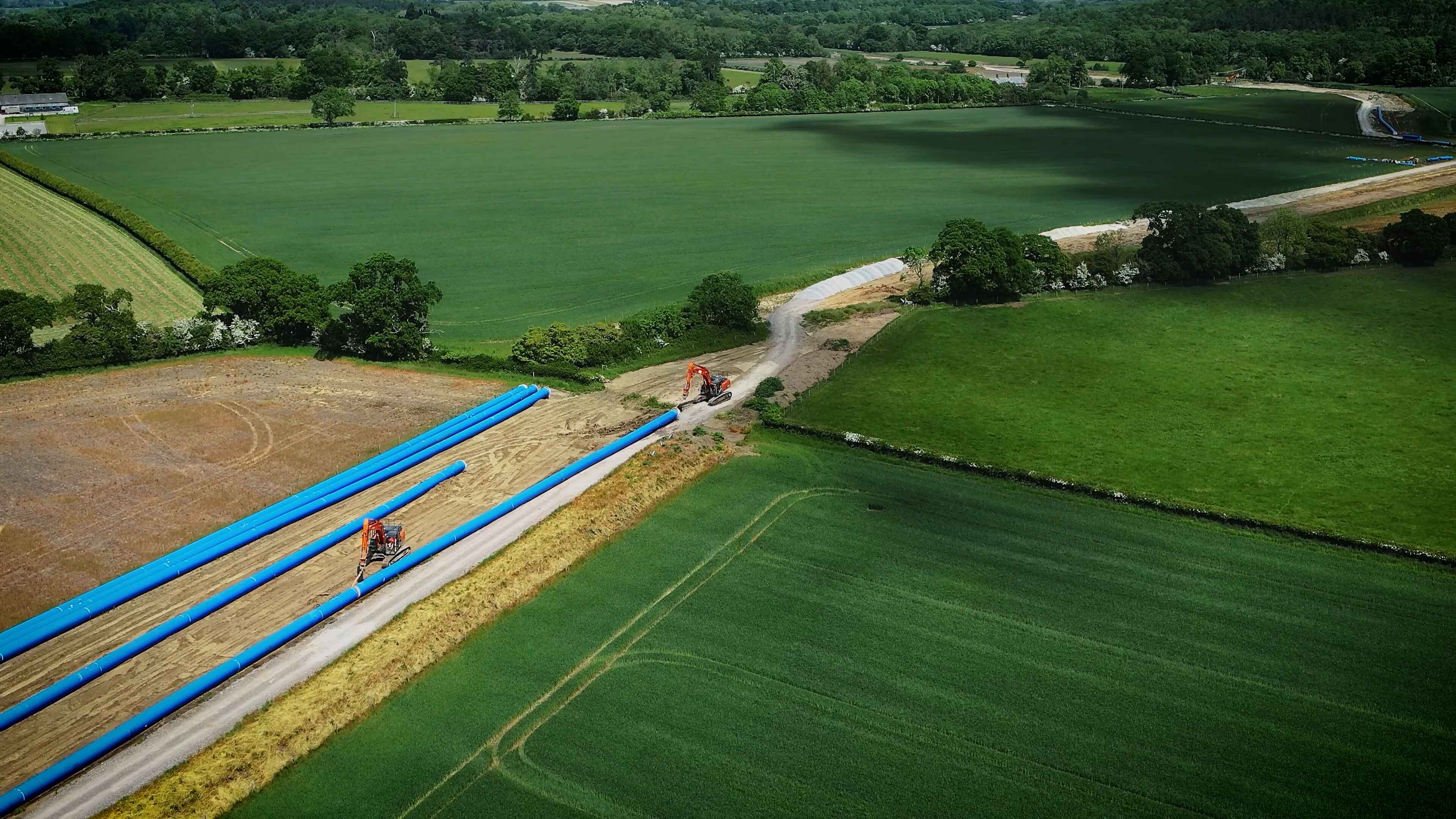 Image shows pipes across a country field during construction