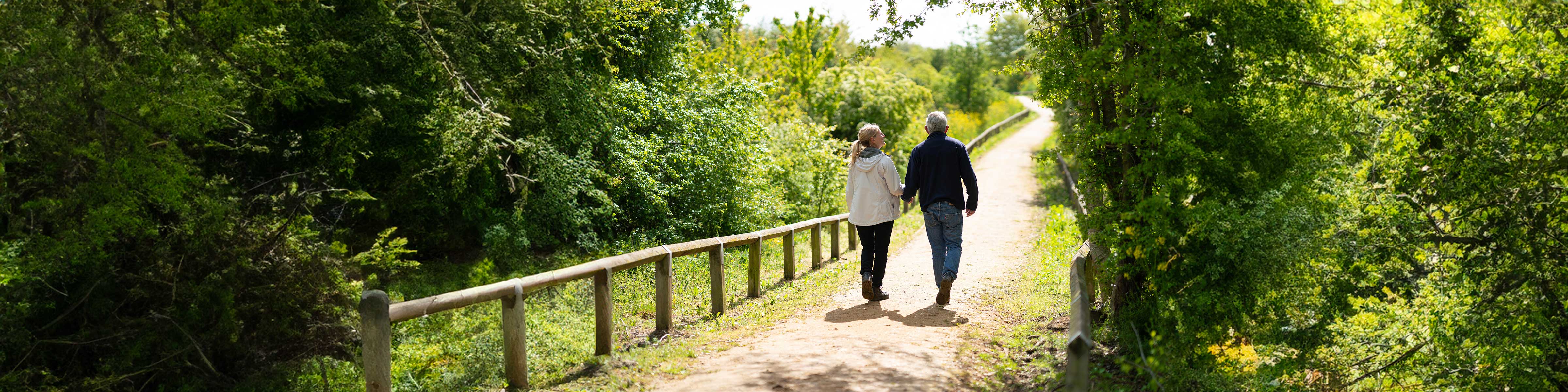Two people walk along a country path in the sunshine