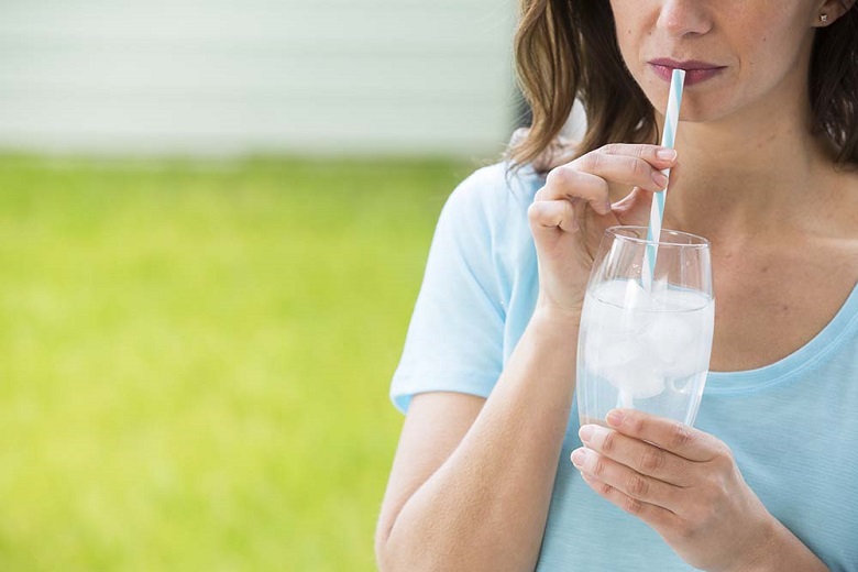 Woman drinking iced water through a straw
