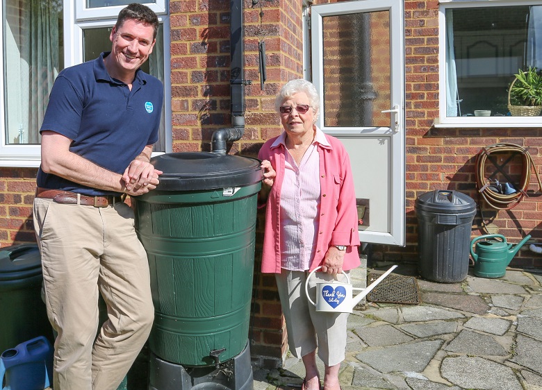 Shirley Cato standing next to her water butt with a Thames Water employee