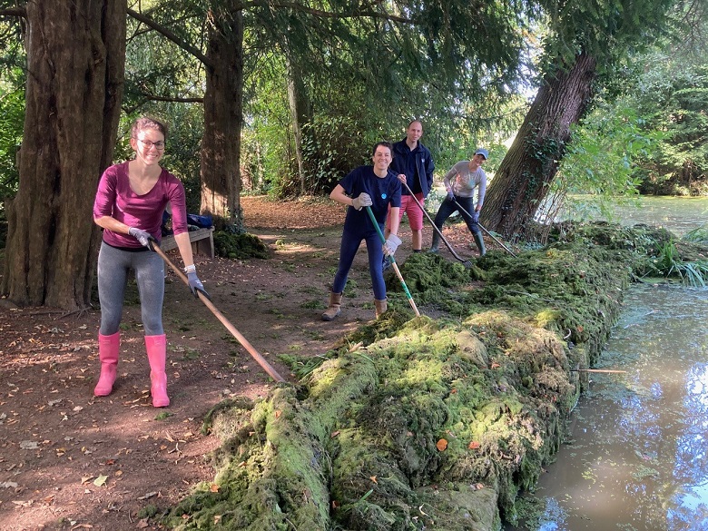 Four people clear pond weed