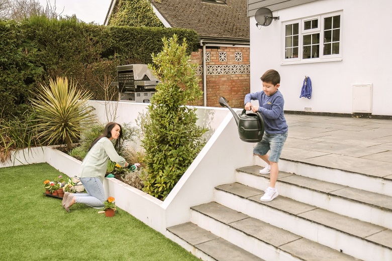 child carries a watering can into the garden