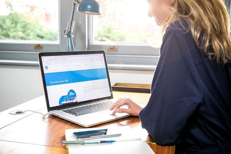 Woman in blue jumper looks at laptop screen