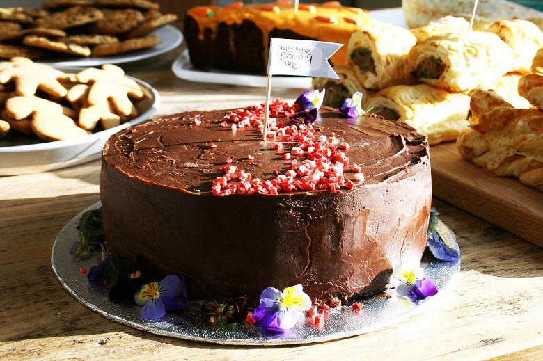A round chocolate cake with purple flowers on it.