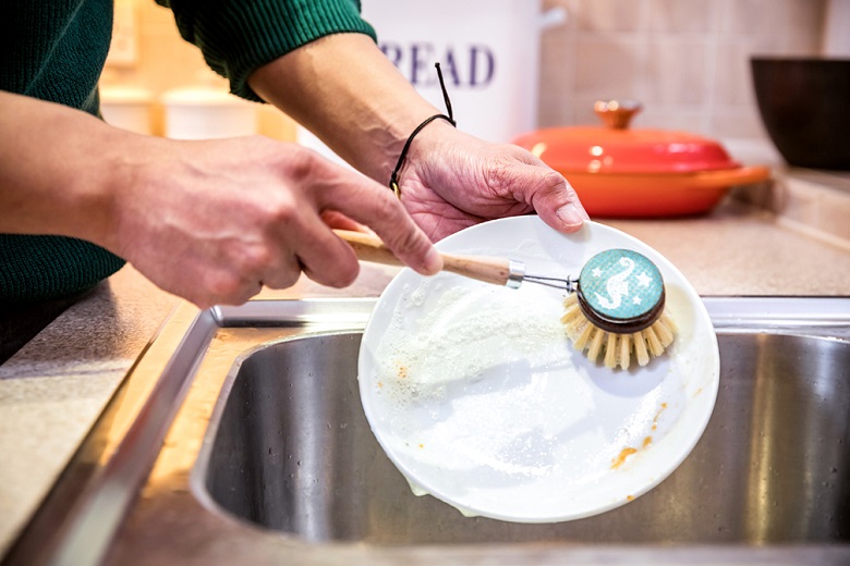 A customer washing a plate at the sink