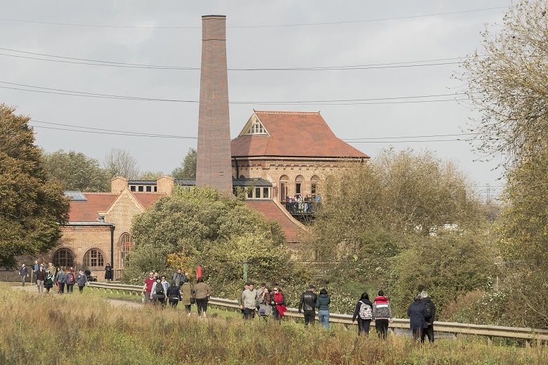 Groups of people walk along a path at Walthamstow Wetlands