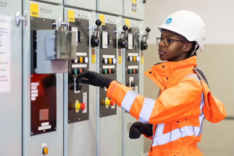Women wearing orange high vis operates a control panel