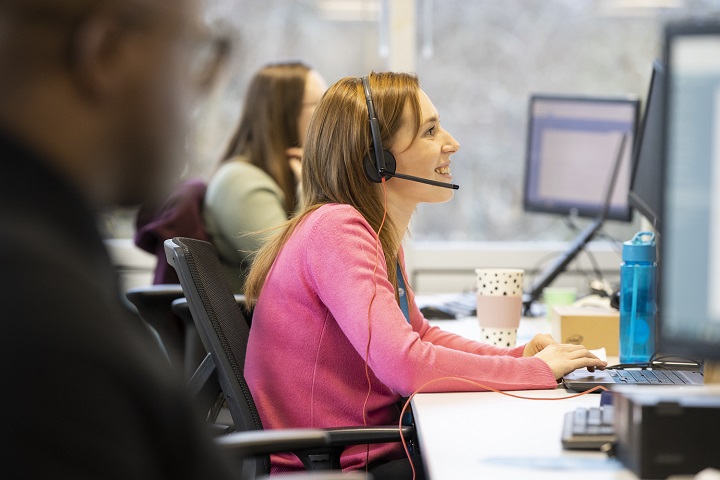 A woman in a pink jumper in a customer call centre