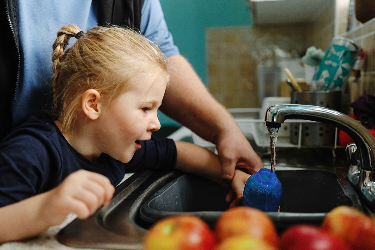 A child fills up her water bottle in the sink