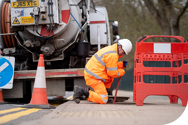 A Thames worker over an open manhole in the street