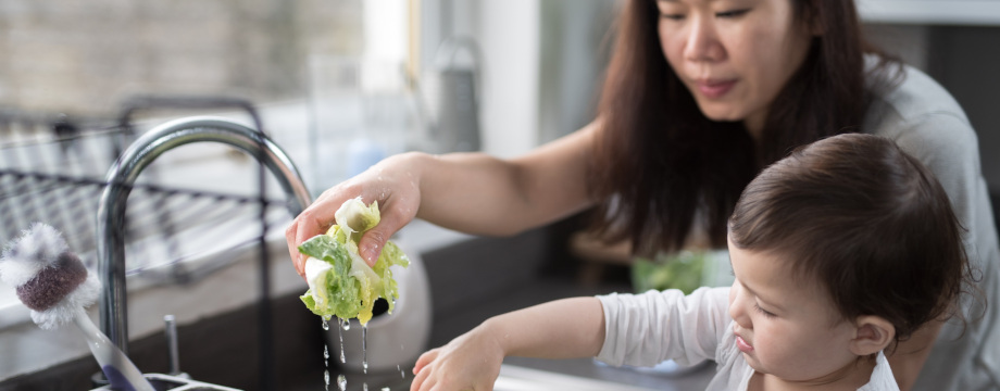 A mother and a child wash vegetables in the sink