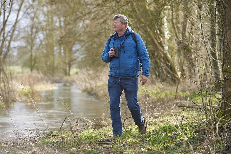 A man birdwatching next to a river
