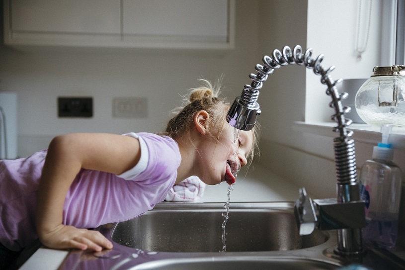 photograph of a child drinking from a tap