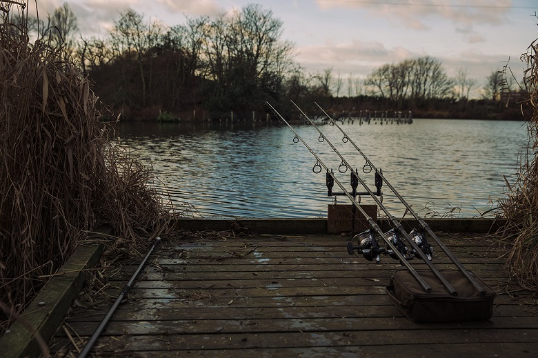 Three fishing rods propped up by a reservoir