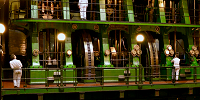 People looking at a large green industrial machine with a large wheel visible in the middle.
