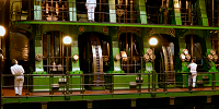People looking at a large green industrial machine with a large wheel visible in the middle. 