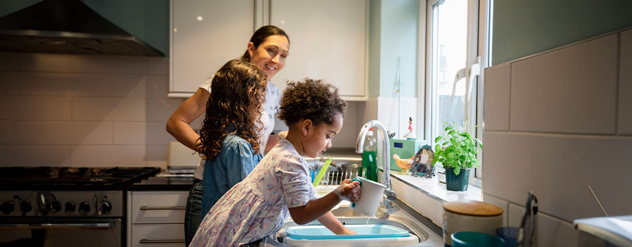 A mother and child washing up at the sink