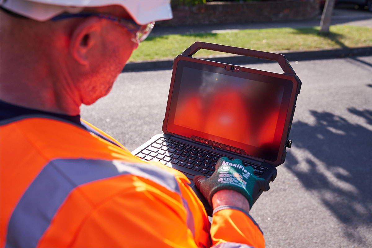 A Thames worker looking at an equipment screen in the street to detect leaks.