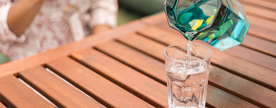 A glass of water being poured from a jug