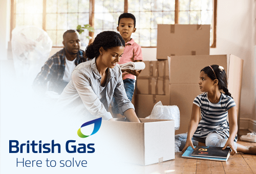 A woman packs a box with her family around helping and other boxes nearby.