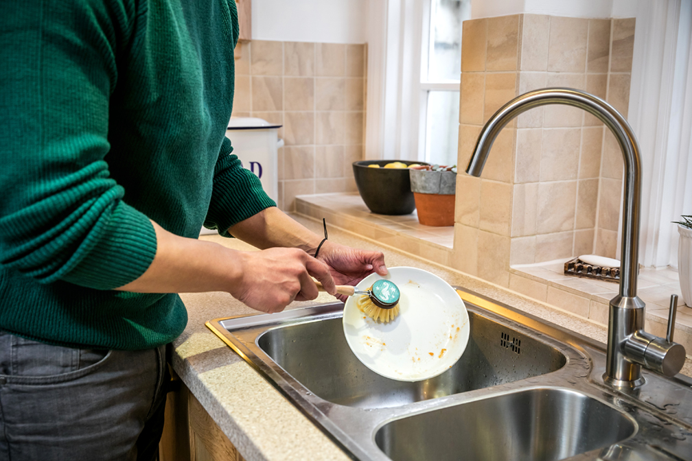 A customer washes up a plate with the tap off