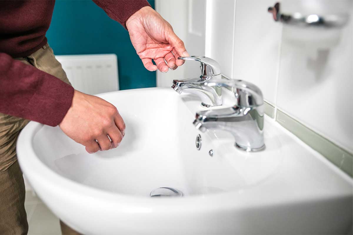 A close-up of hands turning on a bathroom tap
