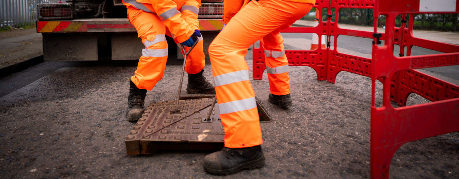 Thames Water engineers lifting a manhole cover