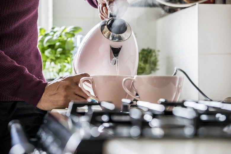 Person pouring water from a kettle into teacups