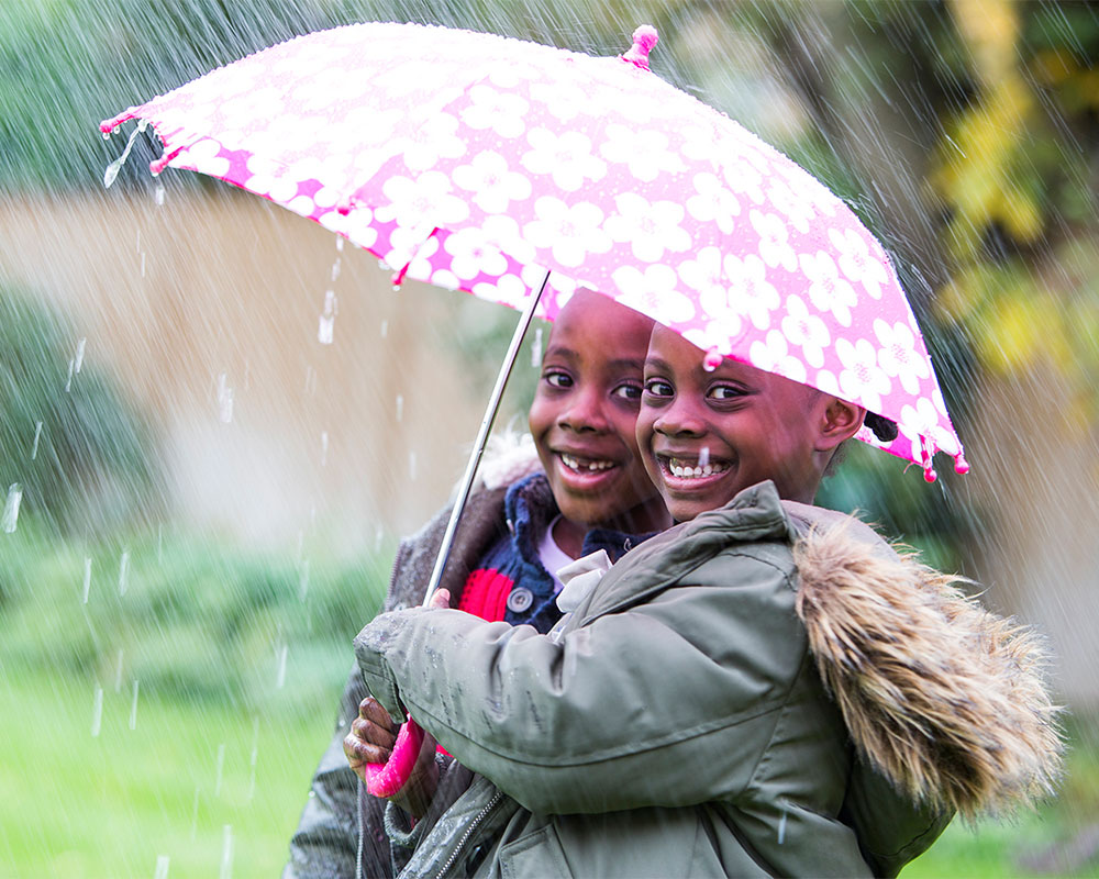 Two boys under an umbrella in the rain