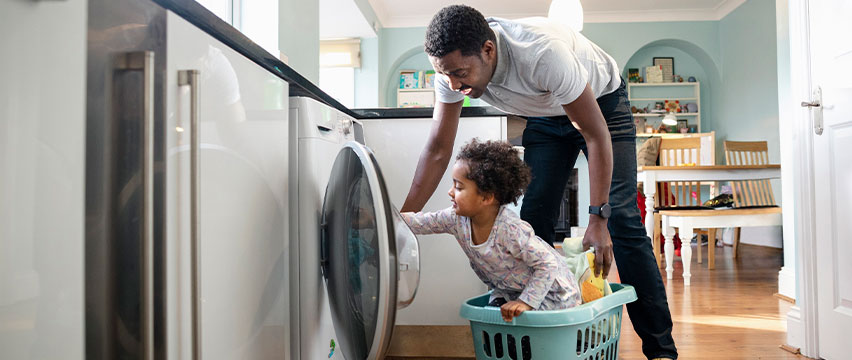 A father and child loading the washing machine