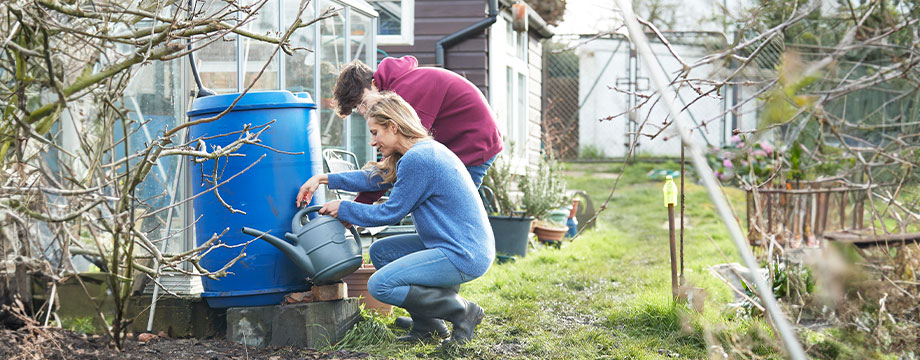 A person fills a watering can from a water butt