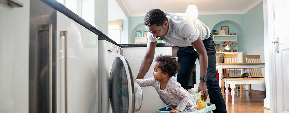 A father and child load the washing machine