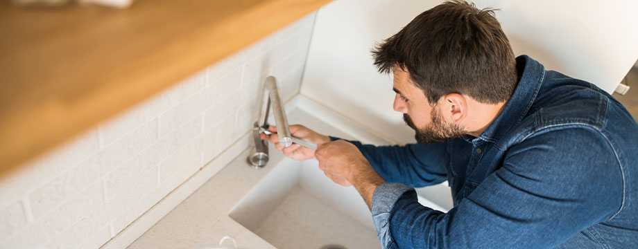 A man fixing a tap at the sink