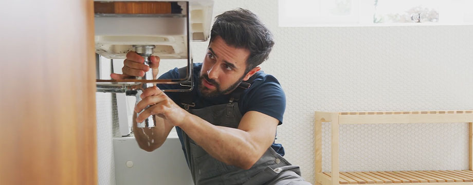 A plumber fixing under a sink