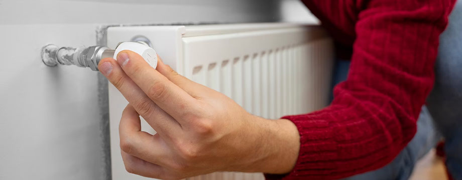 A person adjusts a radiator valve