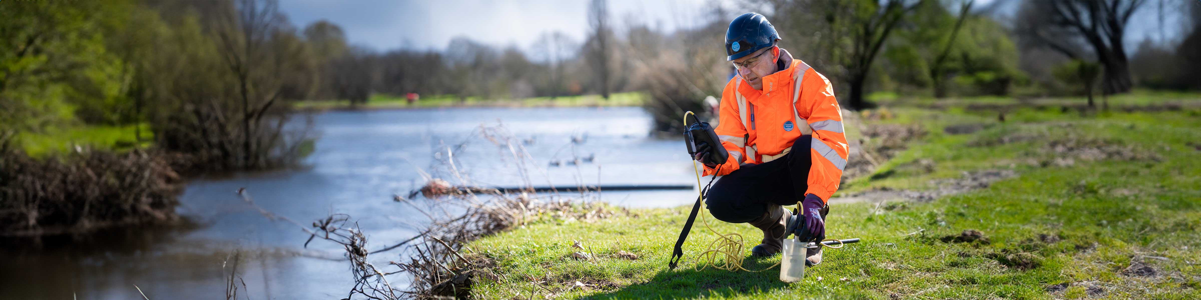 A Thames worker taking a water sample by a river