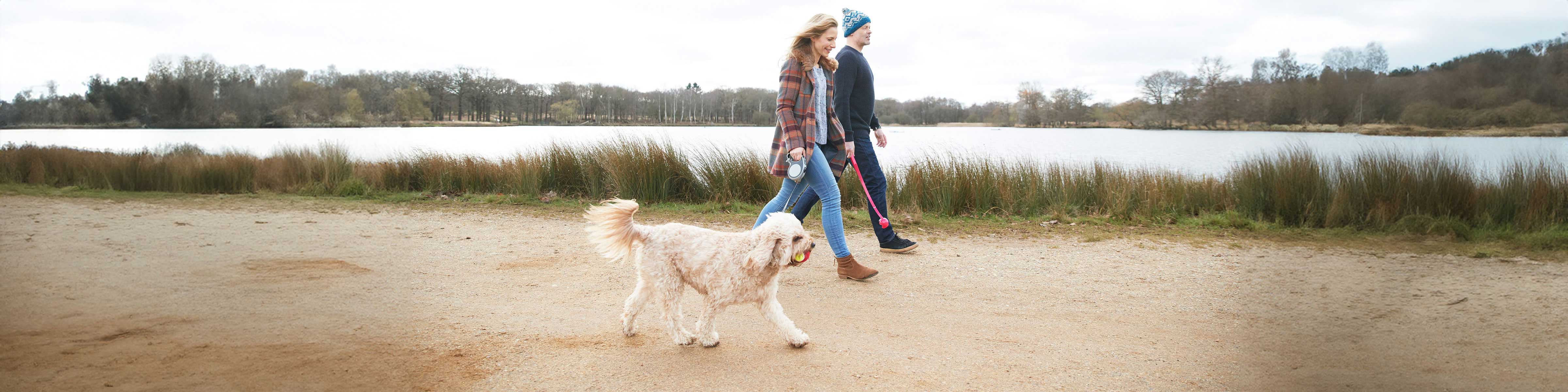 A couple walk their dog next to a reservoir