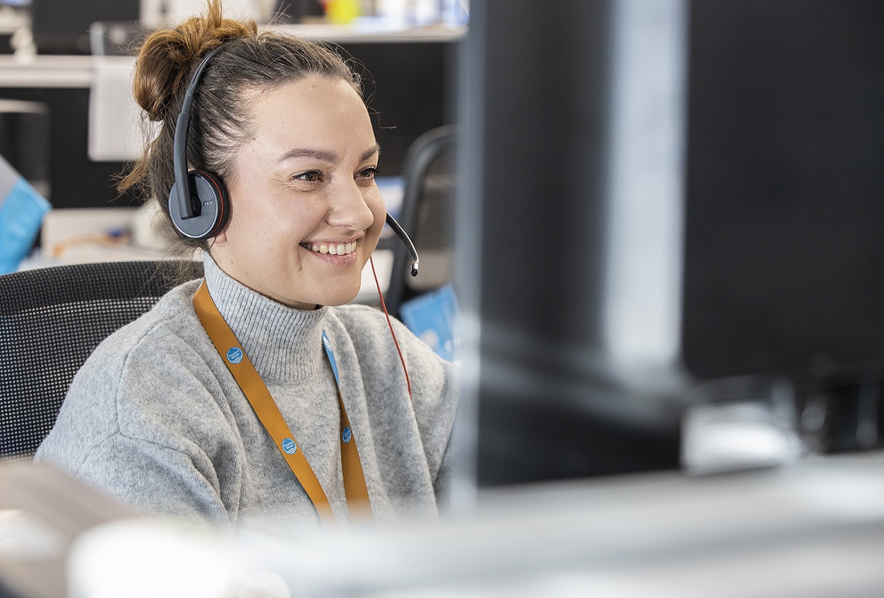 A customer agent smiles while speaking to a customer on the phone