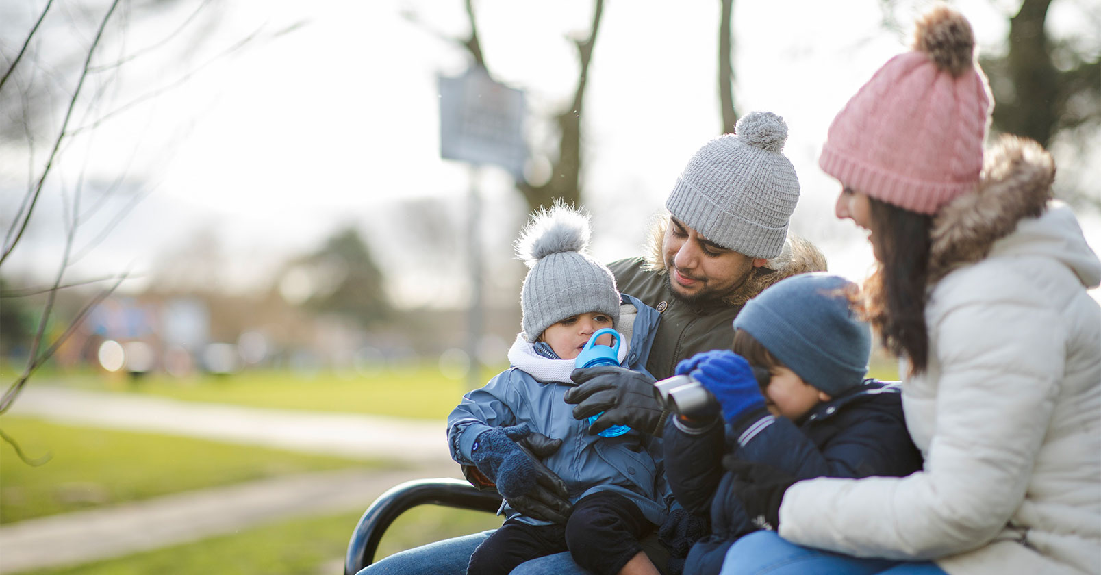 family sitting on a park bench