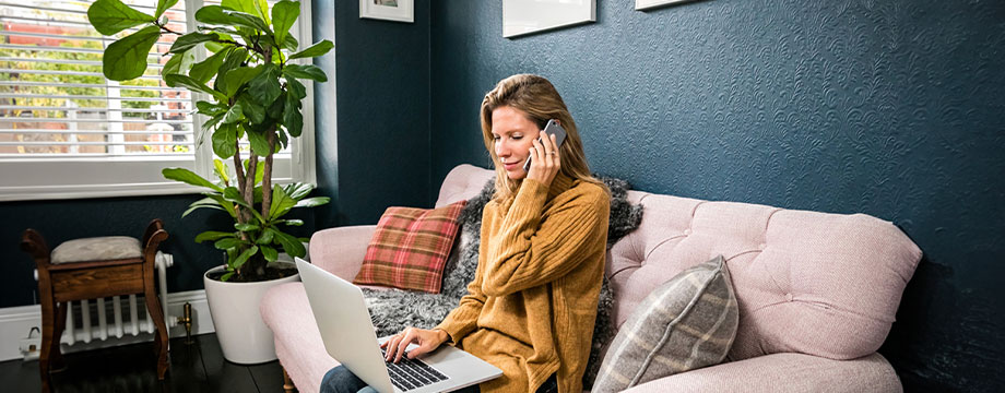 A lady sits on the sofa on her phone