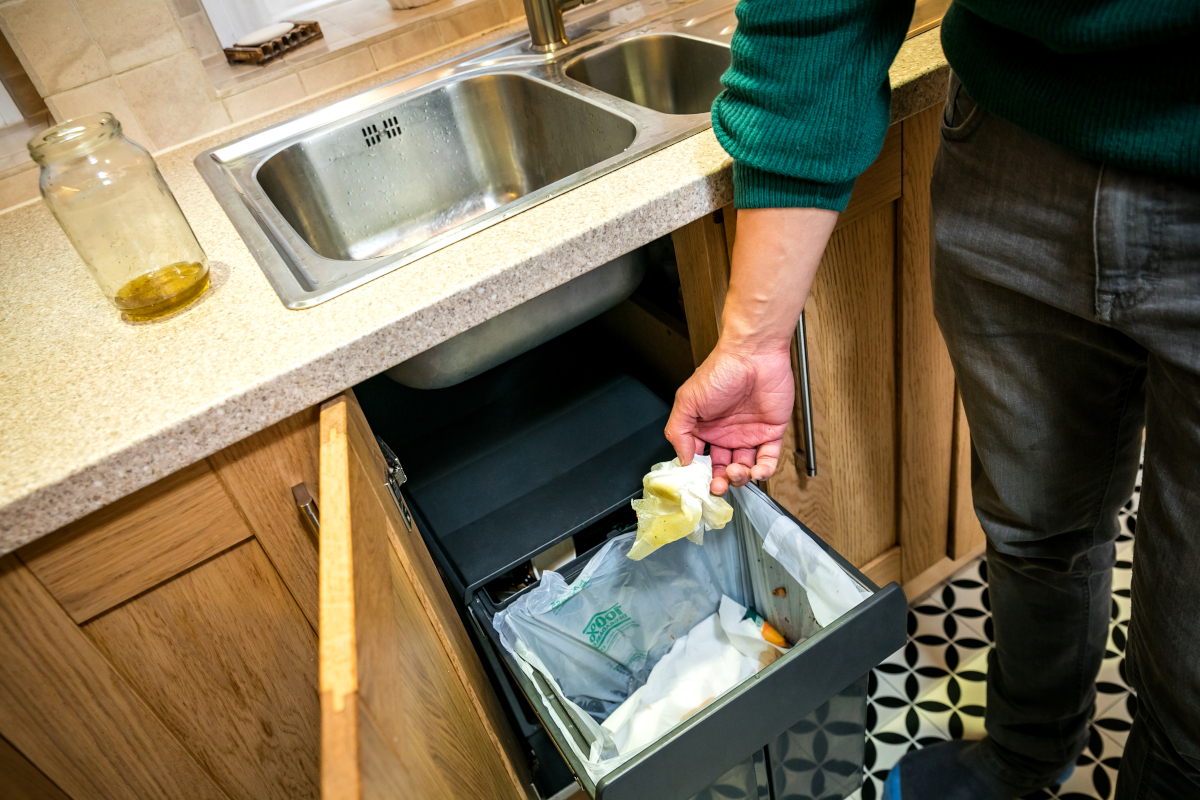 Wiping grease from dishes with kitchen roll and putting it in the bin