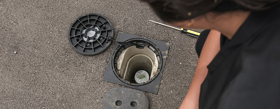 A woman looking at a meter in the ground