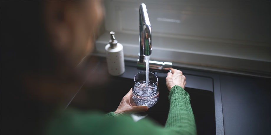 Person filling glass of water from tap