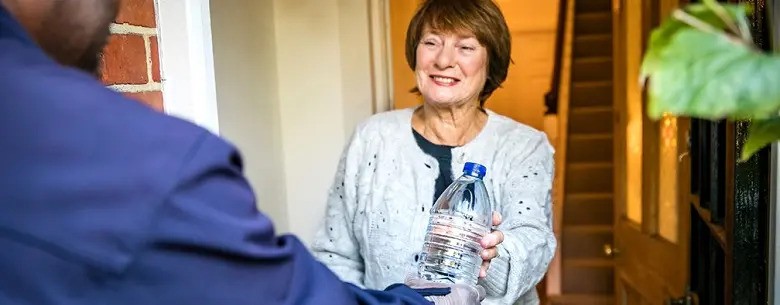 Image of a lady receiving a bottle of water from a man