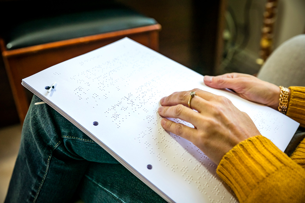 A close up image of a woman reading a braille bill